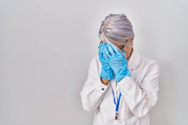Orta yaşlı kadın, gri saçlı, bilim adamı cübbesi giyen, suratını ellerle örten ve ağlayan bir kadın. depresyon kavramı. 