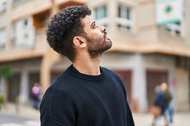 Rahat yüzü olan genç bir Arap caddeye bakıyor.