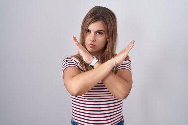 Genç İspanyol kadın, izole edilmiş arka planda duruyor. Reddedilme ifadesi, kollarını kavuşturma, olumsuz işaret, kızgın yüz ifadesi. 