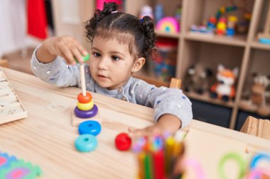 Anaokulundaki masada oturan sevimli İspanyol kız basketbol oyuncaklarıyla oynuyor.