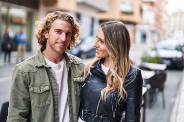 Erkek ve kadın bir arada durarak gülümsüyor.