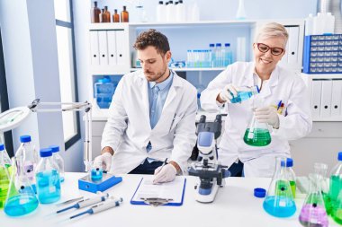 Mother and son scientist partners measuring liquid at laboratory