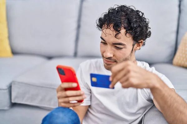 Young Hispanic Man Using Smartphone Credit Card Sitting Floor Home — Stok fotoğraf