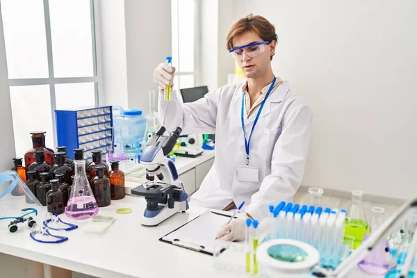 Young Caucasian Man Scientist Holding Test Tube Writing Document Laboratory — Foto de Stock
