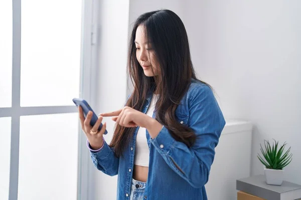 年轻的中国女人站在家里用智能手机 — 图库照片