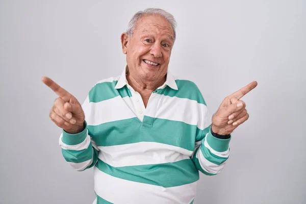白发苍苍的老人站在白色的背景上 带着自信的微笑 手指指向不同的方向 复制广告空间 — 图库照片
