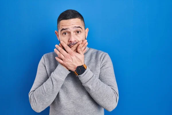 Hispanic Man Står Över Blå Bakgrund Chockad Täcker Munnen Med — Stockfoto