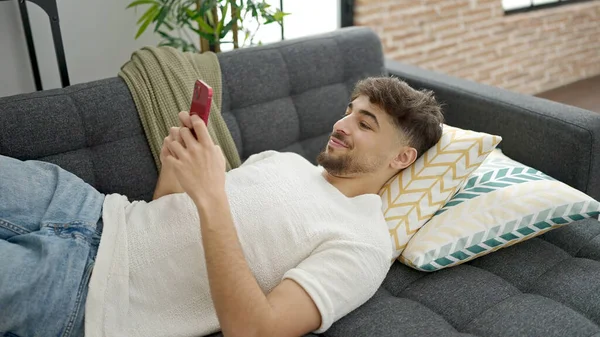 Jonge Arabier Man Met Smartphone Liggend Bank Thuis — Stockfoto