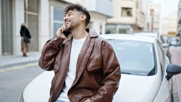 路上で車にもたれているスマートフォンを使っている若いアラブ人男性 — ストック写真