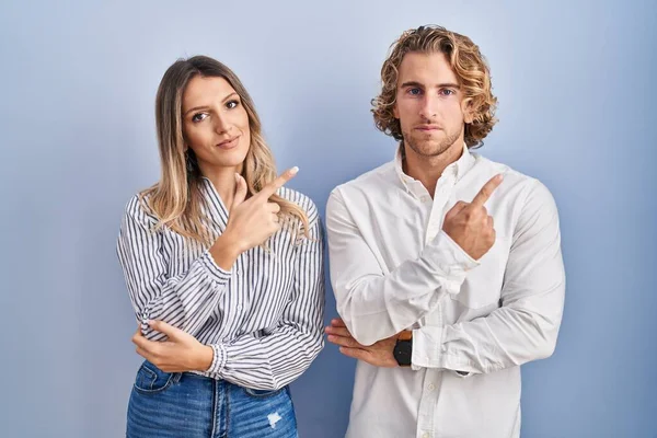 Young Couple Standing Blue Background Pointing Hand Finger Side Showing — Stock Photo, Image