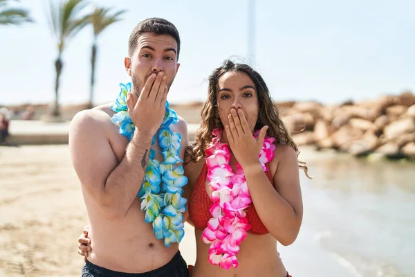若いヒスパニック系のカップルは ビーチで手で口をカバーし ショックを受け ミスを恐れてハワイのネックレスを着て 驚きの表情 — ストック写真