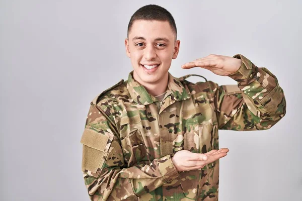 Ung Man Bär Kamouflage Armén Uniform Gest Med Händerna Visar — Stockfoto