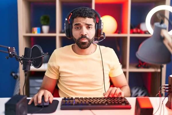 髭を生やしたヒスパニック系の男は ヘッドフォンでビデオゲームをプレイ落ち込んでおり 苦痛のために心配し 怒っていると恐れている 悲しい表情 — ストック写真