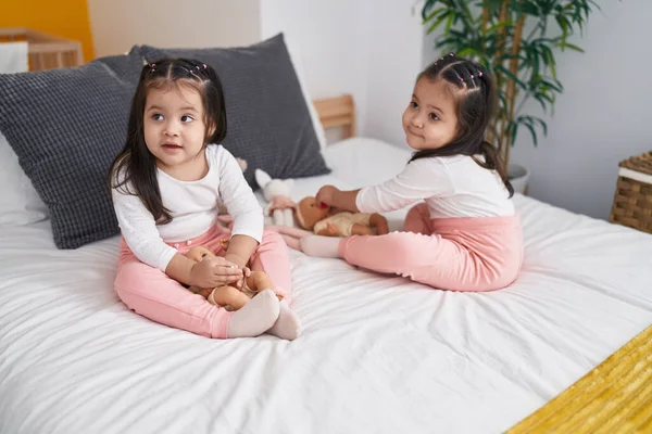 愛らしいです双子女の子プレイとともに赤ちゃん人形座っています上のベッドルーム — ストック写真