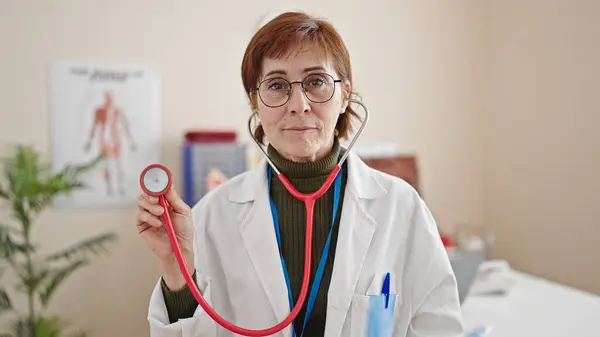 成熟的惊慌失措的女医生在诊所举着听诊器 — 图库照片