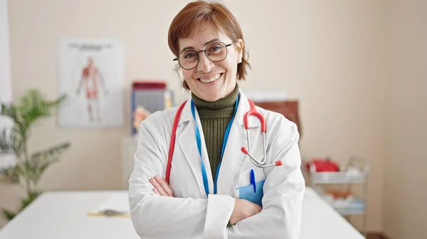 成熟的惊慌失措的女医生微笑着 自信地站在诊所里 双手交叉 — 图库照片