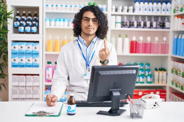 Hispanic Man Curly Hair Working Pharmacy Drugstore Showing Middle Finger — Zdjęcie stockowe