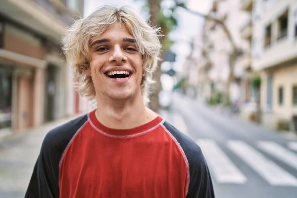 年轻的金发男子自信地站在街上笑 — 图库照片