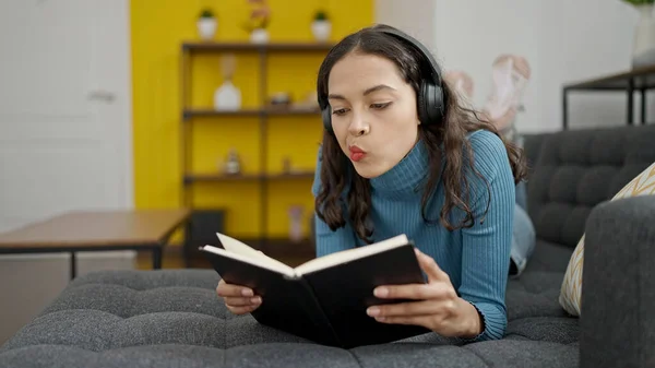 Молодая Красивая Латиноамериканка Читает Книгу Лежащую Дома Диване Наушниках — стоковое фото