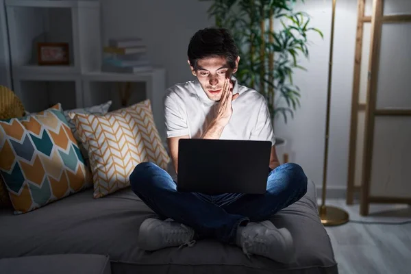 Jovem Hispânico Usando Laptop Casa Noite Mão Boca Dizendo Rumor — Fotografia de Stock