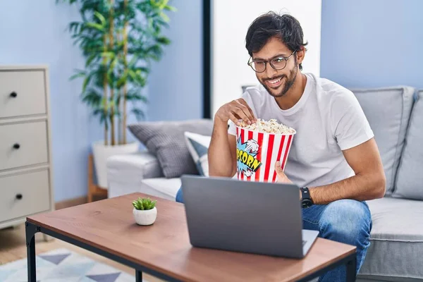 Young Hispanic Man Watching Movie Eating Popcorn Home — Stok fotoğraf