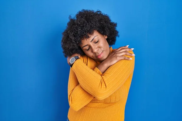 Black Woman Curly Hair Standing Blue Background Hugging Oneself Happy — Stock Photo, Image