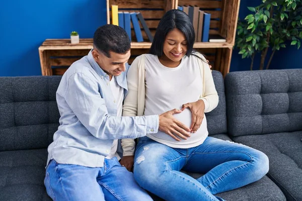 Young Latin Couple Expecting Baby Touching Belly Doing Heart Gesture — Stockfoto