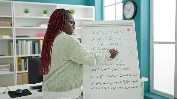編組の髪の先生を持つアフリカの女性は大学図書館で数学のレッスンを教える — ストック写真