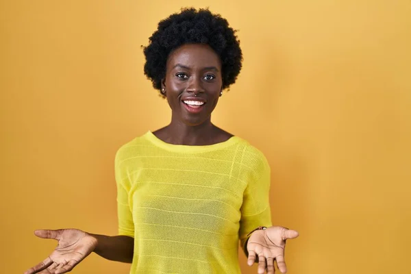 アフリカの若いです若いです女性の上に立って黄色のスタジオ笑顔陽気にオープン腕として友好歓迎 正と自信挨拶 — ストック写真