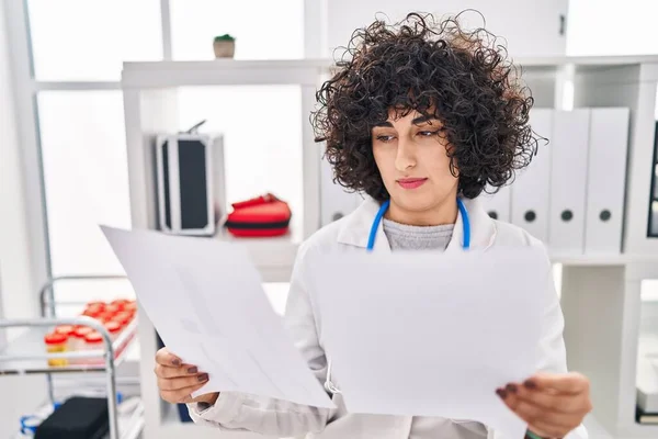 Young Middle East Woman Wearing Doctor Uniform Reading Document Clinic — Fotografie, imagine de stoc
