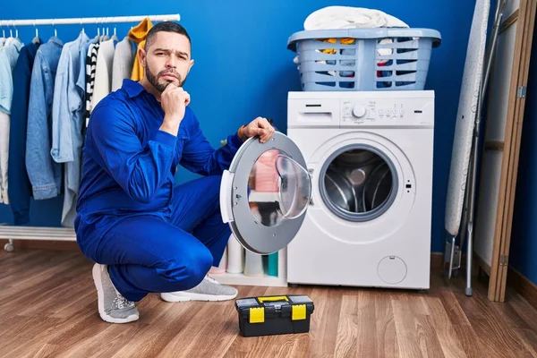 Hispanic Reparatör Arbetar Tvättmaskin Allvarliga Ansikte Tänka Fråga Med Hand — Stockfoto