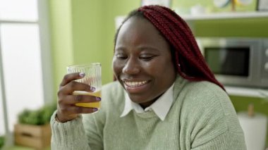Saçları örgülü, yemek salonunda meyve suyu içen Afrikalı kadın.