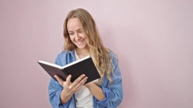 Genç sarışın kadın, kendine güvenen, pembe arka planda kitap okuyan.