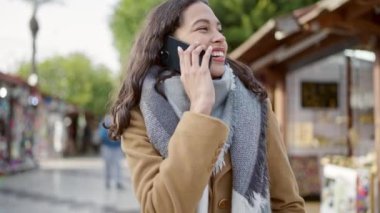 Güzel İspanyol bir kadın akıllı telefondan konuşuyor. Sokak pazarında gülümsüyor.