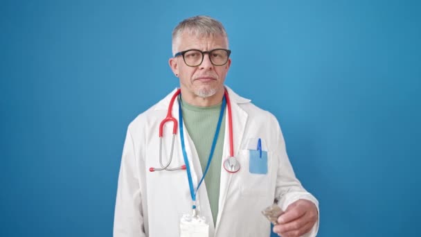 Μεσήλικας Γκριζομάλλης Γιατρός Κρατώντας Χάπια Πάνω Από Απομονωμένο Μπλε Φόντο — Αρχείο Βίντεο