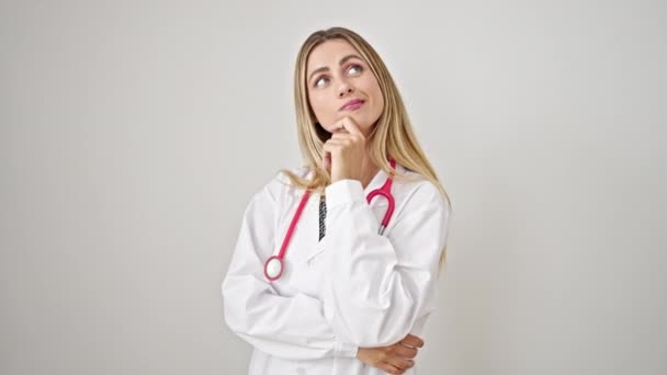 Ung Blondine Kvinde Læge Stående Med Tvivl Udtryk Tænker Isoleret – Stock-video
