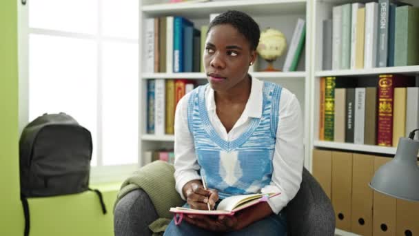 Afrikkalainen Amerikkalainen Nainen Kirjoittaa Muistikirjaan Istuu Tuolilla Kirjaston Yliopistossa — kuvapankkivideo