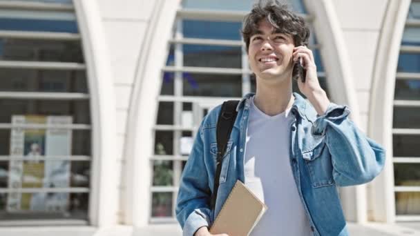 在大学里 他的惊慌失措的年轻学生对着智能手机自信地微笑 — 图库视频影像