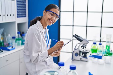 Genç Afrikalı Amerikalı kadın bilim adamı laboratuardaki rapor dökümanına yazdı.