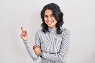 Siyah saçlı İspanyol kadın izole edilmiş arka planda duruyor. Yüzünde kocaman bir gülümseme var. Parmağıyla kameraya bakıyor.. 
