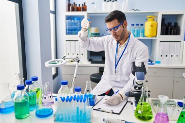 Laboratuvarda test tüpleri tutan genç İspanyol bilim adamı rapor yazıyor.