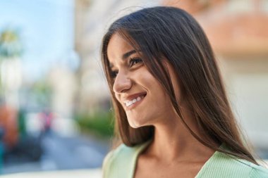 Young beautiful hispanic woman smiling confident looking to the side at street