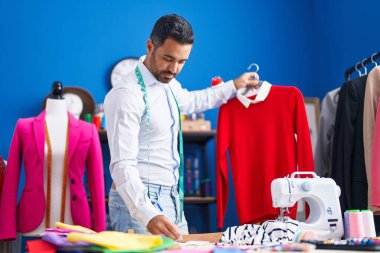 Dikiş atölyesinde tişörtü tutan genç İspanyol terzi kağıda yazmış.