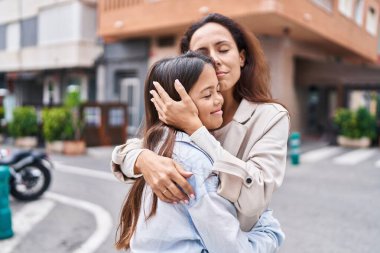 Woman and girl mother and daughter hugging each other at street