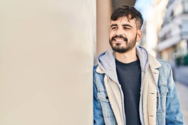 Young hispanic man smiling confident looking to the side at street
