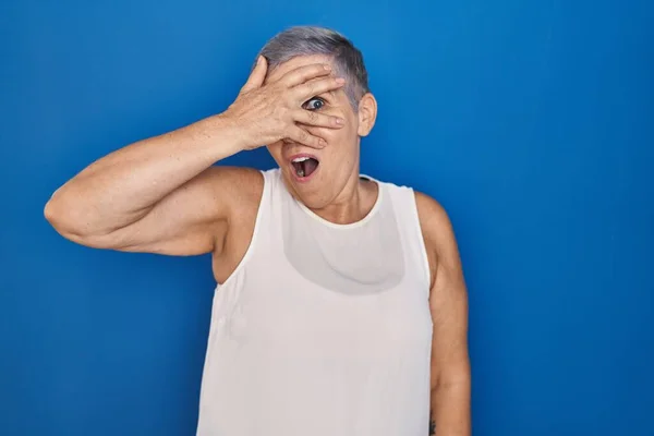 Mujer Caucásica Mediana Edad Pie Sobre Fondo Azul Asomándose Shock — Foto de Stock