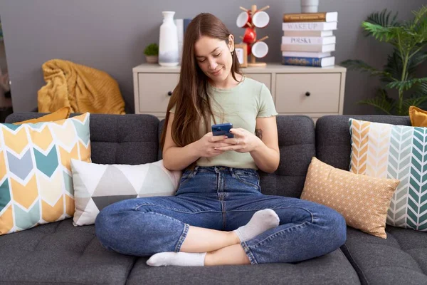 Mujer Hermosa Joven Usando Teléfono Inteligente Sentado Sofá Casa —  Fotos de Stock