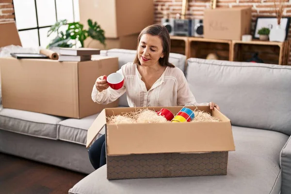 Middle Age Woman Unpacking Cardboard Box Sitting Sofa New Home — Fotografia de Stock