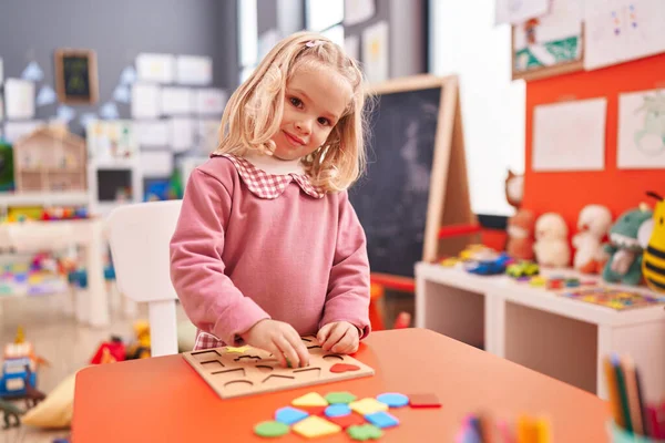 可爱的金发女孩在幼儿园玩数学拼图游戏 — 图库照片