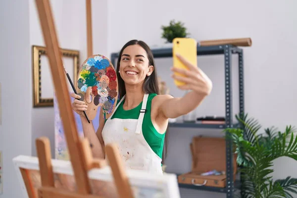 年轻的惊慌失措的女画家面带微笑 自信地在艺术工作室的智能手机前自拍 — 图库照片